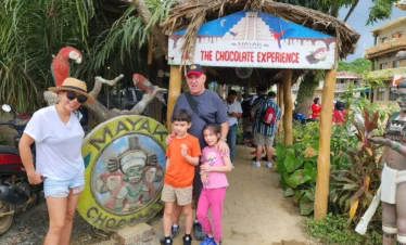 Smiling dad and kids standing outside the Roatan chocolate factory, excited for a fun family vacation in Roatan.