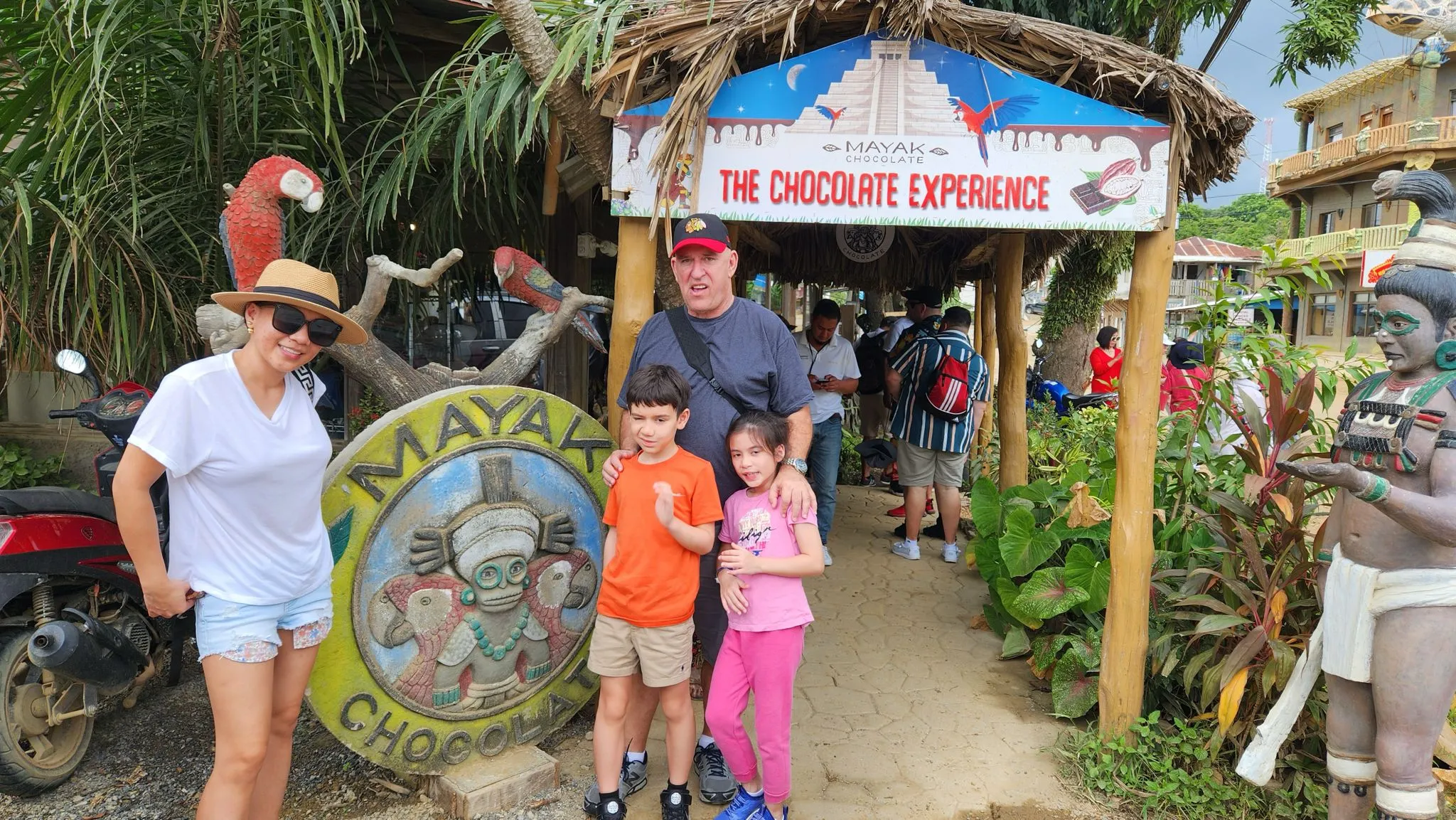 Smiling dad and kids standing outside the Roatan chocolate factory, excited for a fun family vacation in Roatan.