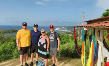 Family of four smiles as they capture a lasting memory of them enjoying the scenic ocean view on our Roatan island tour.