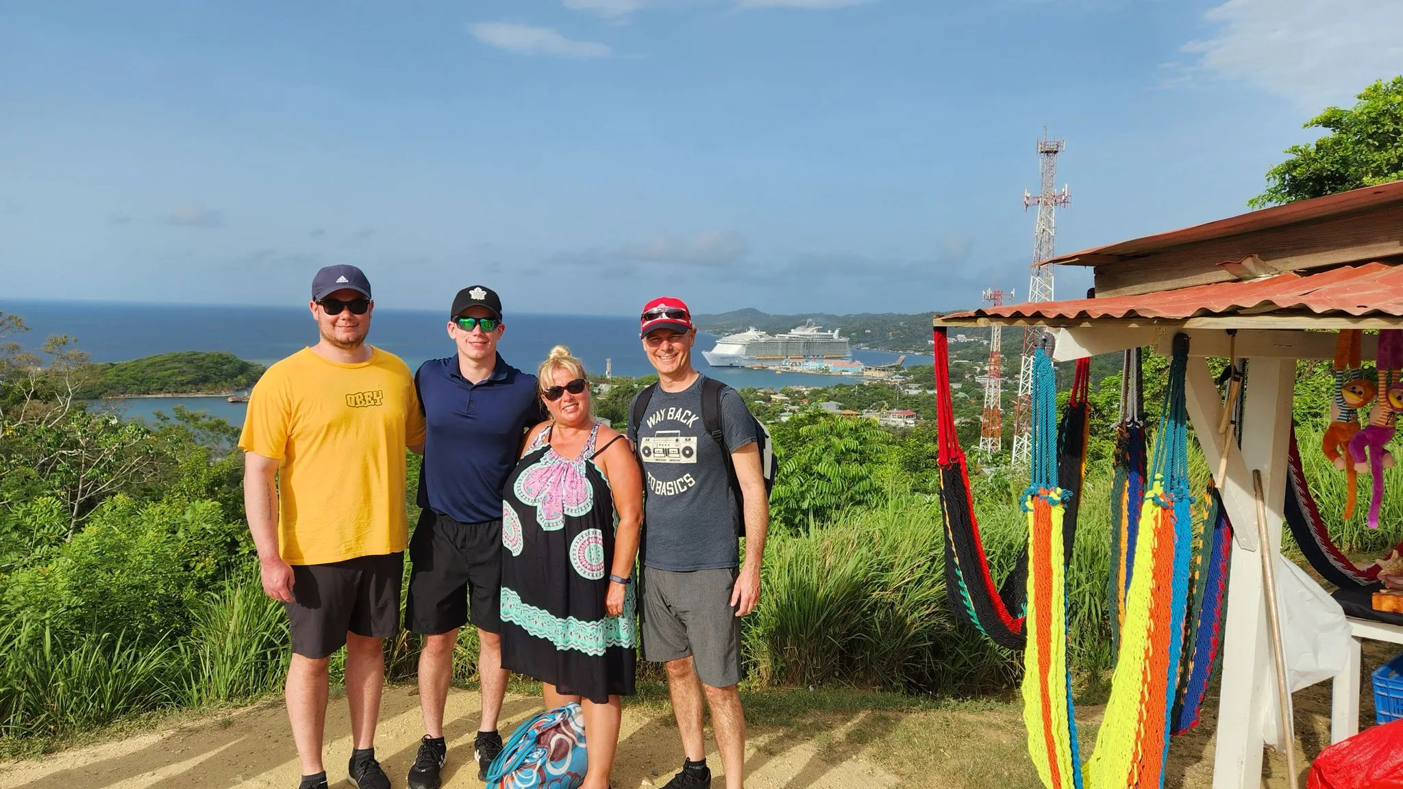 Family of four smiles as they capture a lasting memory of them enjoying the scenic ocean view on our Roatan island tour.